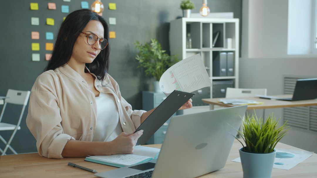 Profissional analisa documentos jurídicos diante do notebook; foto de Vitaly Gariev via Unsplash